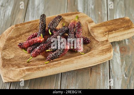 Afghan mulberry black and red on wooden scoop on gray wooden background. Stock Photo