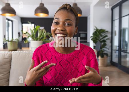 Happy african american woman on video call on couch, talking and gesturing in living room, at home Stock Photo