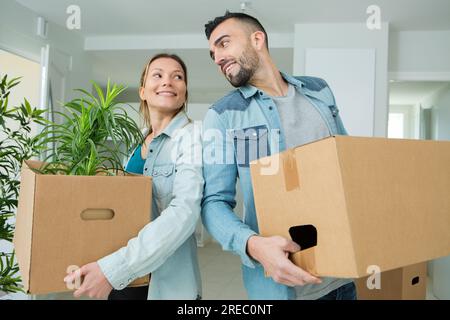 couple moving into a new house carrying cardboard boxes Stock Photo