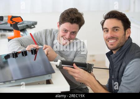 man using a silicone gun with apprentice Stock Photo