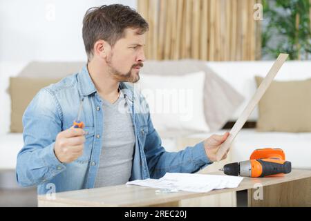 handyman reading an instruction manual with a frustrated expression ...