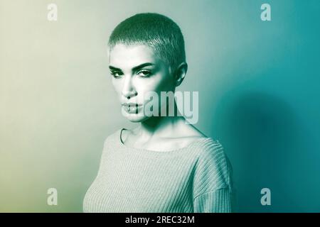 Black and white of young rebellious female model with short blond hair and makeup in knitted sweater looking at camera with confidence in studio Stock Photo