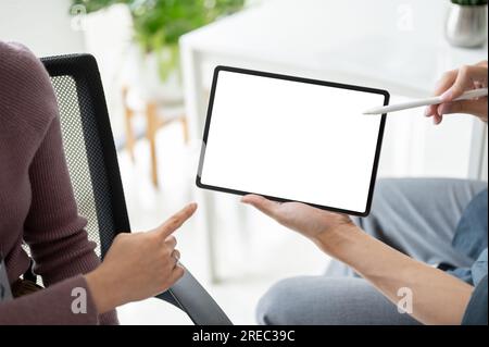 Close-up image of a professional businesswoman discussing and showing some details on a tablet to a male colleague. Tablet white screen mockup for dis Stock Photo