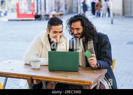 Smiling couple using credit card and laptop to shop online. Stock Photo
