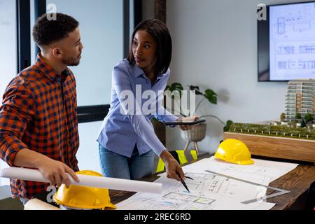 Diverse male and female architects discussing and working on a plan at office Stock Photo