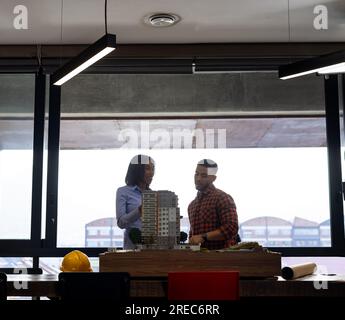 Diverse male and female architects discussing and working on a building model at office Stock Photo
