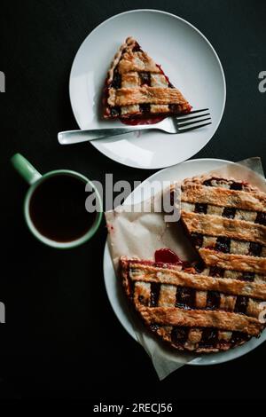 Cherry pie with a cup of regular coffee on black table. Top view, vertical Stock Photo