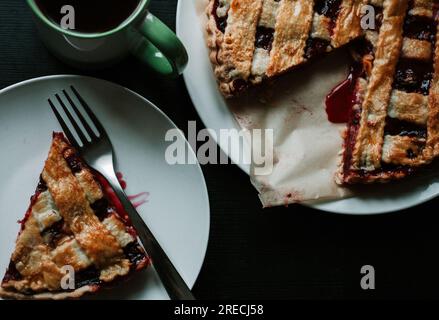 Cherry pie with a cup of regular coffee on black table. Top view Stock Photo