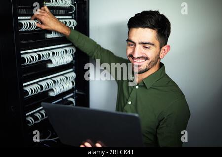 Laptop, maintenance and male technician in a server room for technical repairs by a control box. Technology, engineering and professional man Stock Photo