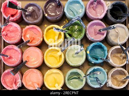 Large group of open old dirty cans of multi-coloured paints, view from above, horizontal crop, abstract artistic background Stock Photo