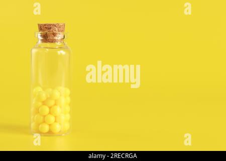 Yellow tablets in a glass bottle, ascorbic acid. Vitamins C in a glass bottle on a yellow background. Epidemic, painkillers, medicine pills and health Stock Photo