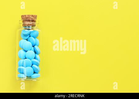 Blue pills in a glass bottle on a yellow background. Healthcare, medical pills and dietary supplements. Pharmaceutical medicines Stock Photo