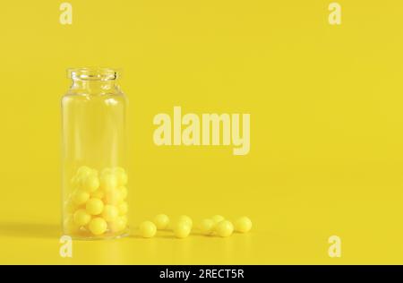 Yellow tablets in a glass bottle, ascorbic acid. Vitamins C on a yellow background. Epidemic, painkillers, medicine pills and healthcare concept Stock Photo