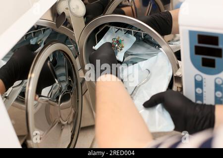 Hands in black gloves holding a medical instrument. Sterilizing box. Sterilization of instruments. Dentist tools. Sterilization procedure. Steam autoc Stock Photo