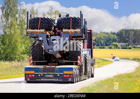 Truck hauls Logset 12F GT forest forwarder on Faymonville low-loader semi trailer, rear view. Salo, Finland. July 20, 2023. Stock Photo