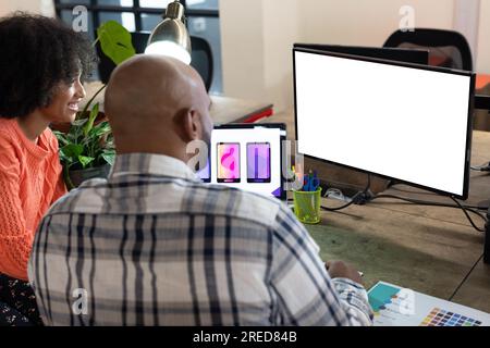 Rear view of happy diverse male and female designers working at computer with copy space in office Stock Photo