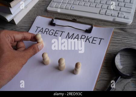 Wooden dolls and text TARGET MARKET on paper clipboard. Business concept Stock Photo