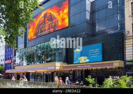 People out and about in Leicester Square pass by the Odeon Luxe cinema. London, England, UK Stock Photo