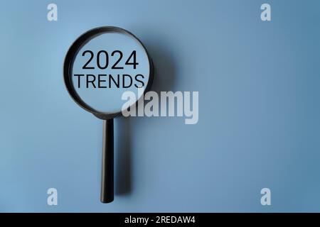 Magnifying glass and text 2024 TRENDS on blue background with copy space Stock Photo