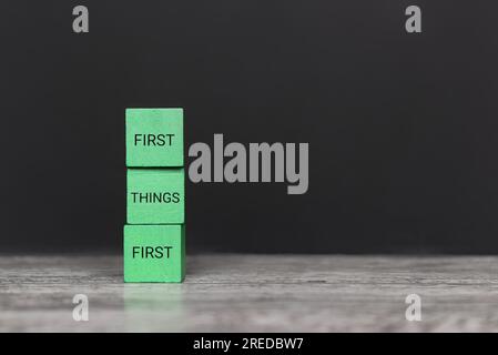 Wooden blocks with text FIRST THINGS FIRST on table. Copy space for text. Stock Photo