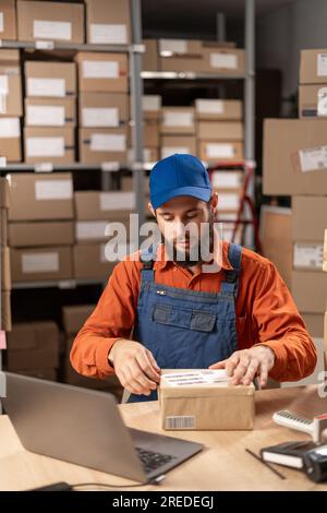 Warehouse worker applying shipping label on parcel boxes. Copy space Stock Photo