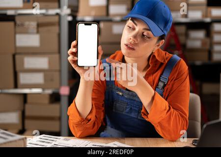 Manager using smartphone in warehouse industry for logistic wholesale storehouse. Mockup blank white screen mobile phone. Online shopping concept. Stock Photo