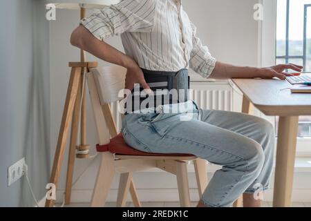 Man wearing back support belt on lower back during exacerbation to treatment of hernia. Stock Photo