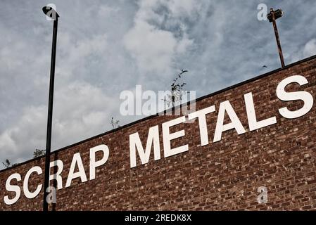 A sign for scrap metals in large white capital letter font on a red brick wall flanked by two lamp posts in Newcastle, England Stock Photo