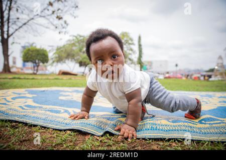 An African newborn with a surprised look crawls on a picnic tablecloth Stock Photo