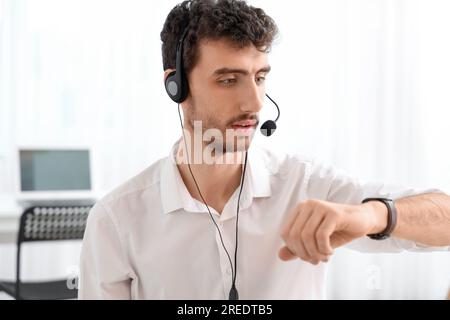 Male technical support agent looking at his watch in office Stock Photo