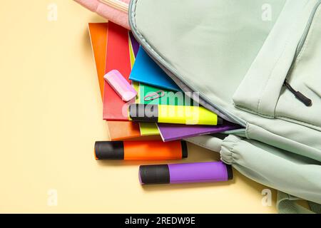 Green school backpack with different stationery on pale yellow background Stock Photo