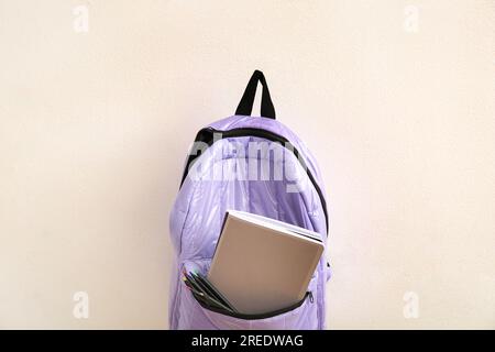 Lilac school backpack with stationery on light background Stock Photo