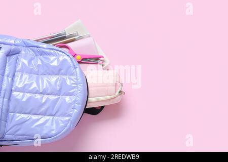Lilac school backpack with stationery on pink background Stock Photo