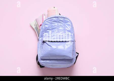 Lilac school backpack with stationery on pink background Stock Photo