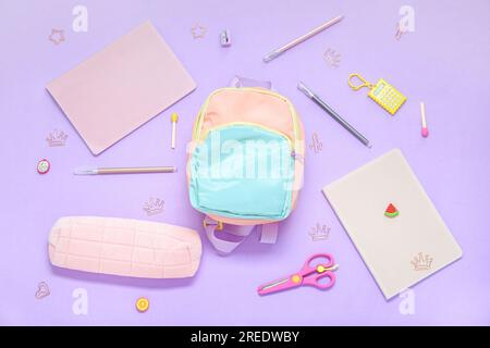 Color school backpack with different stationery on lilac background Stock Photo