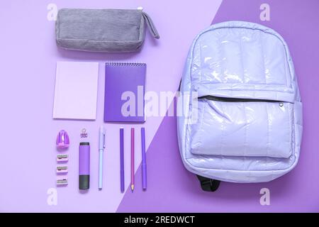 Lilac school backpack with stationery on color background Stock Photo