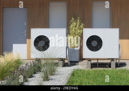 A pair of air source heat pumps, an eco-friendly home heating solution, installed at a contemporary residential property. Stock Photo