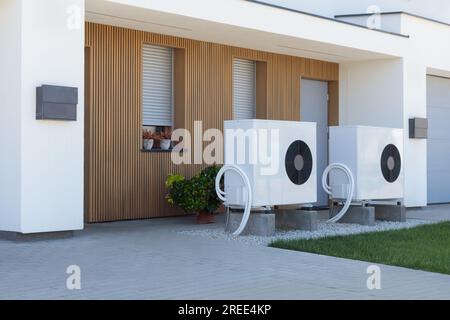 A pair of air source heat pumps, an eco-friendly home heating solution, installed at a contemporary residential property. Stock Photo