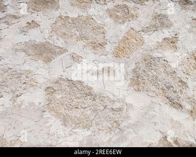 Gray wall of wild limestone and concrete as background. Hand laying. Close-up. Selective focus. Stock Photo