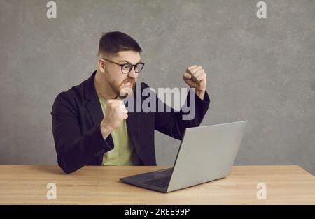 Funny young guy gets furious because of a software problem on his laptop computer Stock Photo