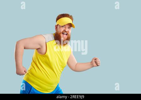 Funny cheerful fat young man in having sports workout, doing exercises, and running Stock Photo