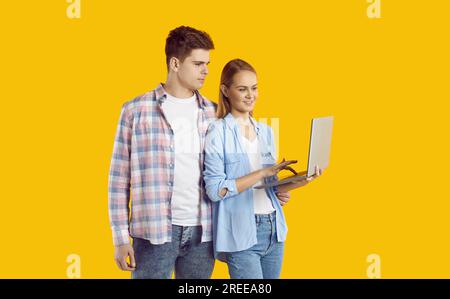 Happy Caucasian couple man and woman stands holding open laptop and looking at monitor Stock Photo