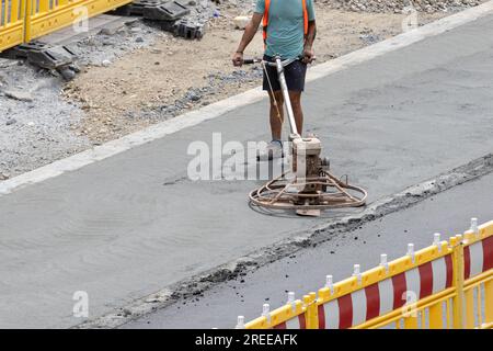 Worker using a machine to polishing concrete surface on a city road Stock Photo