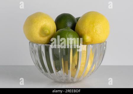 a beautiful cut crystal bowl filled with lemons and limes on a white background with copy space Stock Photo