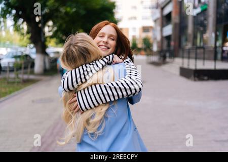 Happy sisters couple having long-awaited meeting after separation. Two cheerful women runs to meet girlfriend after long vacations traveling, trip Stock Photo