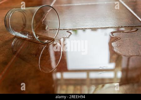 Close-up of a glass water glass spilling water on the ground Stock Photo