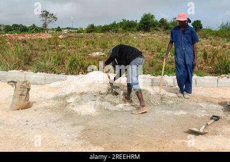 Standing And Looking At A Worker Mixing Mortar Stock Photo