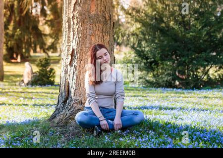 Dreamy young woman sitting in a flower meadow Stock Photo