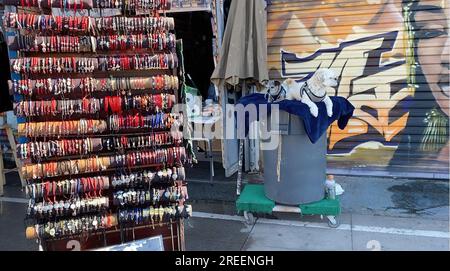 Dogs sitting by a souvenir shop with bracelets in Venice, California Stock Photo