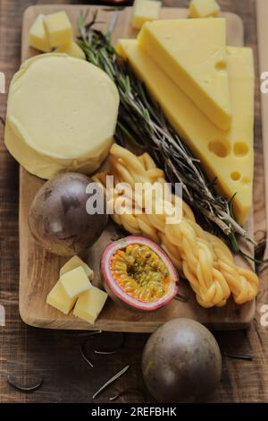 Mazdar cheese triangles, gouda cheese cubes,chechil smoked cheese.assorted cheese on a wooden board with herbs and fruits.Hard and soft cheeses Stock Photo